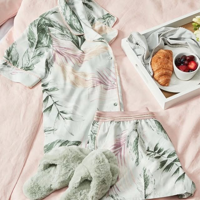 Leaf-print short pyjama set on a pink bed with breakfast tray